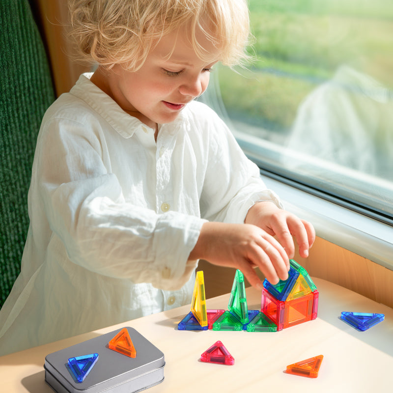 Kind bouwt concentratiespel met magnetische tegels in de trein